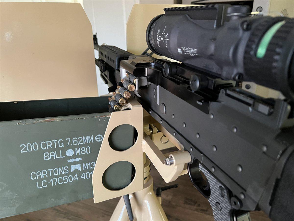 Belt-fed 7.62mm machine gun with magnified optic on a tripod